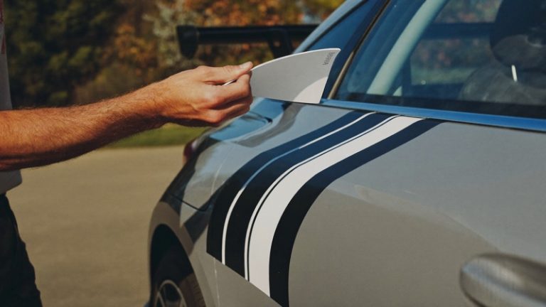 Pose d'une bande adhésive sur l'aile d'une voiture