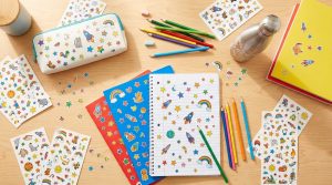 Fournitures scolaires décorées de stickers colorés vues de dessus sur un bureau en bois