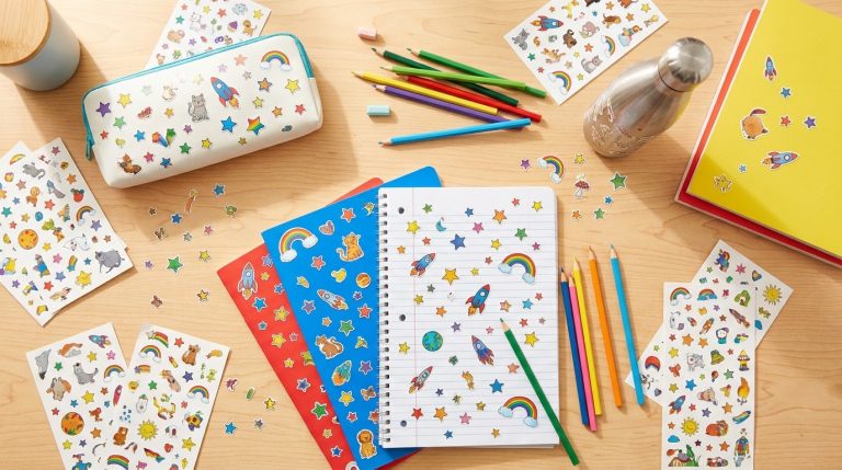 Fournitures scolaires décorées de stickers colorés vues de dessus sur un bureau en bois