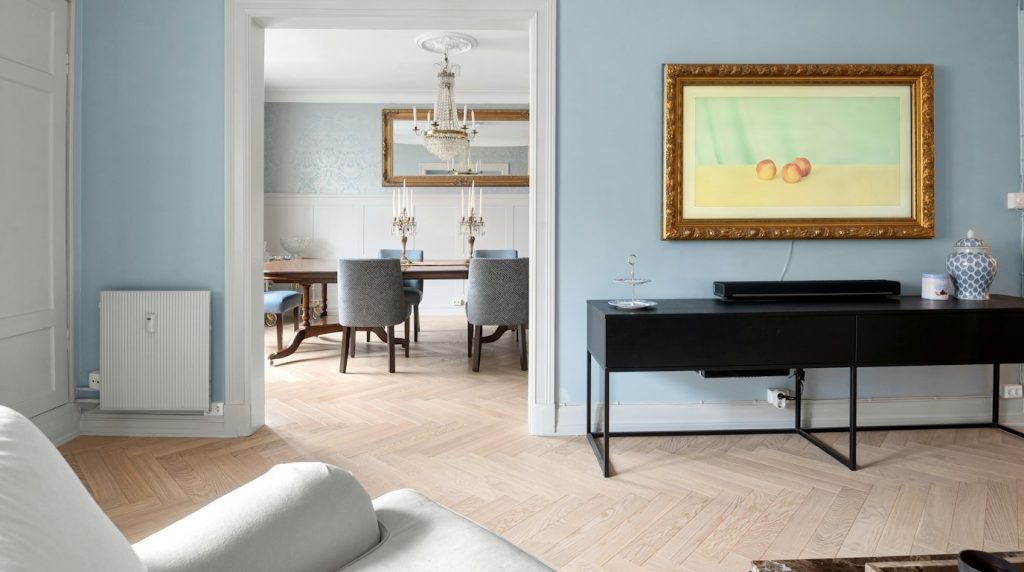 Salon aux murs peints en bleu moyen avec console noire et parquet en chevrons clair